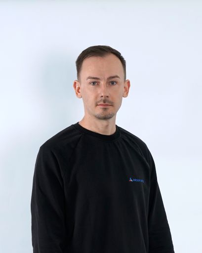 Bild von einem Mann mit braunen Haaren. Er trägt einen schwarzen Pullover mit der Aufschrift „Orgami Sistec“. + Logo. Er steht vor einem weißen Hintergrund.