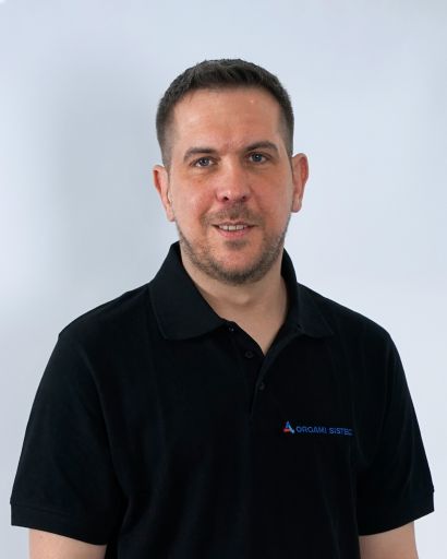 Bild von einem Mann mit braunen Haaren. Er trägt ein schwarzes T-Shirt mit der Aufschrift „Orgami Sistec“ + Logo. Stehend vor einem weißen Hintergrund.