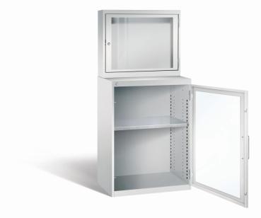 Lichtgrauer Computerschrank mit abschließbarem Sichtfenster im oberen Bereich und geöffneter Stahltür mit Sichtfenster im unteren Bereich. Im unteren Fach befindet sich ein höhenverstellbarer Fachboden. Der Schrank steht vor weißem Hintergrund.
