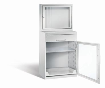 Lichtgrauer Computerschrank mit abschließbarem Sichtfenster im oberen Bereich und geöffneter Acrylglas-Stahltür im unteren Bereich mit Schublade und einem höhenverstellbarer Fachboden sowie Auszugsboden. Der Schrank steht vor weißem Hintergrund.