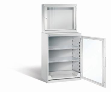 Lichtgrauer Computerschrank mit abschließbarem Sichtfenster im oberen Bereich und geöffneter Acrylglas-Stahltür im unteren Bereich und 2 höhenverstellbarer Fachboden sowie Auszugsboden. Der Schrank steht vor weißem Hintergrund.