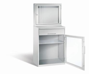 Lichtgrauer Computerschrank mit abschließbarem Sichtfenster im oberen Bereich und geöffneter Acrylglas-Stahltür im unteren Bereich mit Schublade und einem höhenverstellbarer Fachboden. Der Schrank steht vor weißem Hintergrund.