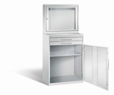Lichtgrauer Computerschrank mit abschließbarem Sichtfenster im oberen Bereich und geöffneter Stahltür mit zwei Schubladen im unteren Bereich und einem höhenverstellbarer Fachboden. Der Schrank steht vor weißem Hintergrund.