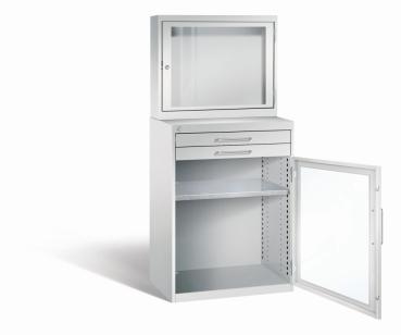 Lichtgrauer Computerschrank mit abschließbarem Sichtfenster im oberen Bereich und geöffneter Acrylglas-Stahltür mit 2 Schubladen im unteren Bereich und einem höhenverstellbarer Fachboden. Der Schrank steht vor weißem Hintergrund.