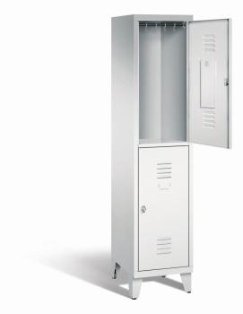 Ein lichtgrauer Garderobenschrank mit einem Abteil, zwei Fächern sowie integrierten Kleiderstangen mit Kleiderhaken, dessen obere Tür geöffnet ist. Er steht auf Stahlblechfüßen vor weißem Hintergrund.