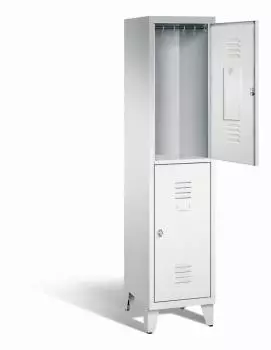Ein lichtgrauer Garderobenschrank mit einem Abteil, zwei Fächern sowie integrierten Kleiderstangen mit Kleiderhaken, dessen obere Tür geöffnet ist. Er steht auf Stahlblechfüßen vor weißem Hintergrund.