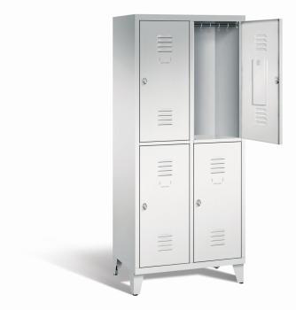 Ein lichtgrauer Garderobenschrank mit zwei Abteilen, vier Fächern sowie integrierten Kleiderstangen mit Kleiderhaken, dessen obere rechte Tür geöffnet ist. Er steht auf Stahlblechfüßen vor weißem Hintergrund.