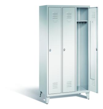 Ein lichtgrauer Garderobenschrank mit drei Abteilen, drei Fächern sowie integrierten Kleiderstangen mit Kleiderhaken, dessen rechte Tür geöffnet ist. Er steht auf Stahlblechfüßen vor weißem Hintergrund.
