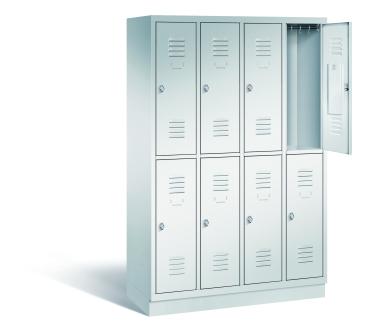 Ein lichtgrauer Garderobenschrank mit vier Abteilen, acht Fächern sowie integrierten Kleiderstangen mit Kleiderhaken, dessen obere rechte Tür geöffnet ist. Er steht auf einem Stahlblechsockel vor weißem Hintergrund.