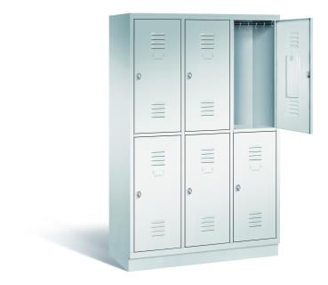 Ein lichtgrauer Garderobenschrank mit drei Abteilen, sechs Fächern sowie integrierten Kleiderstangen mit Kleiderhaken, dessen obere rechte Tür geöffnet ist. Er steht auf einem Stahlblechsockel vor weißem Hintergrund.