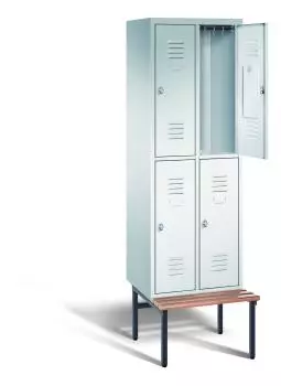 Ein lichtgrauer Garderobenschrank mit zwei Abteilen, vier Fächern sowie integrierten Kleiderstangen mit Kleiderhaken, dessen obere rechte Tür geöffnet ist. Er steht auf einer unter- und vorgebauten Sitzbank vor weißem Hintergrund.