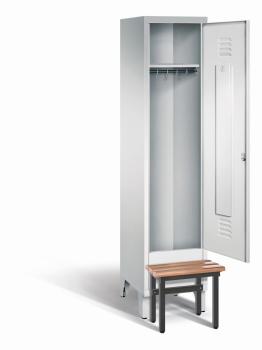 Ein lichtgrauer Garderobenschrank mit einem Abteil, einem Fach sowie integrierten Kleiderstangen mit Kleiderhaken, dessen Tür geöffnet ist. Er steht auf Stahlblechfüßen und hat eine vorgebaute Sitzbank vor weißem Hintergrund.