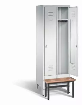 Ein lichtgrauer Garderobenschrank mit zwei Abteilen, zwei Fächern sowie integrierten Kleiderstangen mit Kleiderhaken, dessen rechte Tür geöffnet ist. Er steht auf Stahlblechfüßen und hat eine vorgebaute Sitzbank vor weißem Hintergrund.