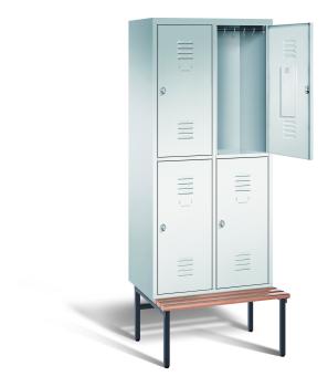 Ein lichtgrauer Garderobenschrank mit zwei Abteilen, vier Fächern sowie integrierten Kleiderstangen mit Kleiderhaken, dessen obere rechte Tür geöffnet ist. Er steht auf einer unter- und vorgebauten Sitzbank vor weißem Hintergrund.