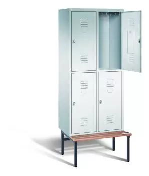 Ein lichtgrauer Garderobenschrank mit zwei Abteilen, vier Fächern sowie integrierten Kleiderstangen mit Kleiderhaken, dessen obere rechte Tür geöffnet ist. Er steht auf einer unter- und vorgebauten Sitzbank vor weißem Hintergrund.