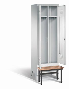 Ein lichtgrauer Garderobenschrank mit zwei Abteilen, zwei Fächern sowie integrierten Kleiderstangen mit Kleiderhaken, dessen Türen geöffnet sind. Er steht auf Stahlblechfüßen und hat eine vorgebaute Sitzbank vor weißem Hintergrund.