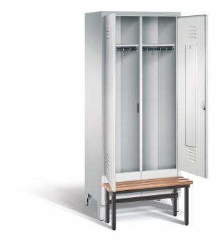 Ein lichtgrauer Garderobenschrank mit zwei Abteilen, zwei Fächern sowie integrierten Kleiderstangen mit Kleiderhaken, dessen Türen geöffnet sind. Er steht auf Stahlblechfüßen und hat eine vorgebaute Sitzbank vor weißem Hintergrund.