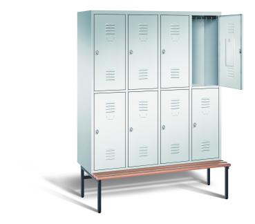 Ein lichtgrauer Garderobenschrank mit vier Abteilen, acht Fächern sowie integrierten Kleiderstangen mit Kleiderhaken, dessen obere rechte Tür geöffnet ist. Er steht auf einer unter- und vorgebauten Sitzbank vor weißem Hintergrund.