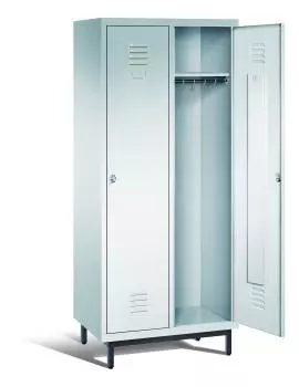 Ein lichtgrauer Garderobenschrank mit zwei Abteilen, zwei Fächern sowie integrierten Kleiderstangen mit Kleiderhaken, dessen rechte Tür geöffnet ist. Er steht auf Stahlrohrfüßen vor weißem Hintergrund.