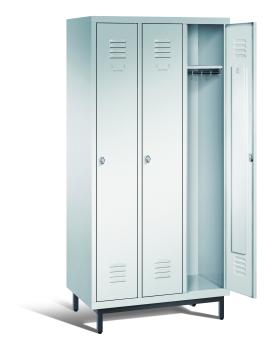 Ein lichtgrauer Garderobenschrank mit drei Abteilen, drei Fächern sowie integrierten Kleiderstangen mit Kleiderhaken, dessen rechte Tür geöffnet ist. Er steht auf Stahlrohrfüßen vor weißem Hintergrund.