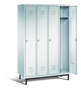 Ein lichtgrauer Garderobenschrank mit vier Abteilen, vier Fächern sowie integrierten Kleiderstangen mit Kleiderhaken, dessen rechte Tür geöffnet ist. Er steht auf Stahlrohrfüßen vor weißem Hintergrund.