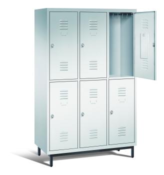Ein lichtgrauer Garderobenschrank mit drei Abteilen, sechs Fächern sowie integrierten Kleiderstangen mit Kleiderhaken, dessen obere rechte Tür geöffnet ist. Er steht auf Stahlrohrfüßen vor einem weißen Hintergrund.