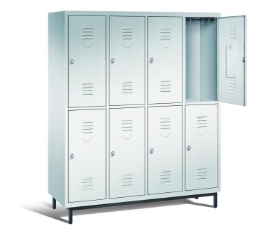 Ein lichtgrauer Garderobenschrank mit vier Abteilen, acht Fächern sowie integrierten Kleiderstangen mit Kleiderhaken, dessen obere rechte Tür geöffnet ist. Er steht auf Stahlrohrfüßen vor weißem Hintergrund.