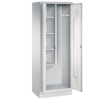 Ein lichtgrauer Putzmittelschrank mit zwei Abteilen, sowie einer integrierten Kleiderstange mit Kleiderhaken. Die beiden Türen sind geöffnet, im linken Abteil befinden sich vier Fachböden. Er steht auf einem Stahlblechsockel vor weißem Hintergrund.