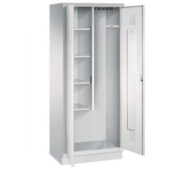Ein lichtgrauer Putzmittelschrank mit zwei Abteilen, sowie einer integrierten Kleiderstange mit Kleiderhaken. Die beiden Türen sind geöffnet, im linken Abteil befinden sich vier Fachböden. Er steht auf einem Stahlblechsockel vor weißem Hintergrund.