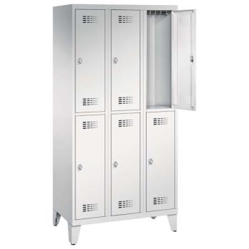 Ein lichtgrauer Garderobenschrank mit drei Abteilen, sechs Fächern sowie integrierten Kleiderstangen mit Kleiderhaken, dessen obere rechte Tür geöffnet ist. Er steht auf Stahlblechfüßen vor weißem Hintergrund.