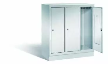 Lichtgrauer Fächerschrank mit drei Abteilen, drei Türen und drei Fächern. Integrierte Kleiderstange mit Kleiderhaken im Spind für praktische Aufbewahrung. Ideal zur Lagerung von Kleidung und anderen Gegenständen. Steht vor einem weißen Hintergrund.