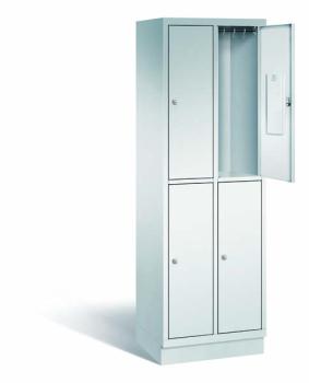 Ein lichtgrauer Fächerschrank mit zwei Abteilen, vier Türen und vier Fächern. Integrierte Kleiderstangen mit Kleiderhaken im Spind für praktische Aufbewahrung. Ideal zur Lagerung von Kleidung und anderen Gegenständen. Steht vor einem weißen Hintergrund.