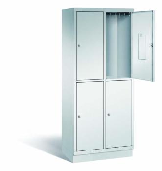 Ein lichtgrauer Fächerschrank mit zwei Abteilen, vier Türen und vier Fächern. Integrierte Kleiderstangen mit Kleiderhaken im Spind für praktische Aufbewahrung. Ideal zur Lagerung von Kleidung und anderen Gegenständen. Steht vor einem weißen Hintergrund.