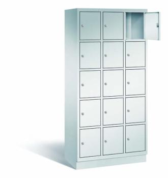 Ein lichtgrauer Fächerschrank mit drei Abteilen, 15 Türen und 15 Fächern, ideal zur Aufbewahrung von Gegenständen. Die obere rechte Tür ist geöffnet, während der Schrank vor einem weißen Hintergrund steht.