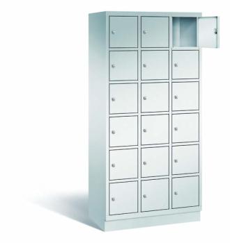 Ein lichtgrauer Fächerschrank mit drei Abteilen, 18 Türen und 18 Fächern, ideal zur Aufbewahrung von Gegenständen. Die obere rechte Tür ist geöffnet, während der Schrank vor einem weißen Hintergrund steht.