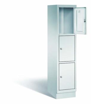 Ein lichtgrauer Fächerschrank mit einem Abteil, drei Türen und drei Fächern, ideal zur Aufbewahrung von Gegenständen. Die oberste der drei Türen steht offen und er steht vor einem weißen Hintergrund.