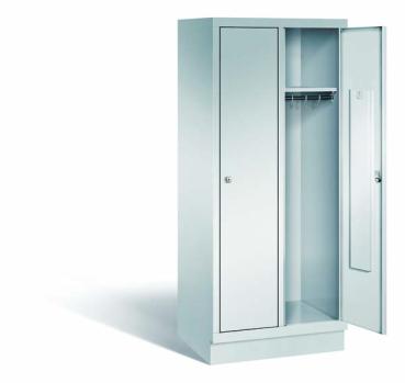 Lichtgrauer Fächerschrank mit zwei Abteilen, zwei Türen und zwei Fächern. Darunter integrierte Kleiderstangen mit Kleiderhaken für praktische Aufbewahrung. Ideal zur Lagerung von Kleidung und anderen Gegenständen. Steht vor einem weißen Hintergrund.