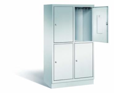 Ein lichtgrauer Fächerschrank mit zwei Abteilen, vier Türen und vier Fächern. Integrierte Kleiderstangen mit Kleiderhaken im Spind für praktische Aufbewahrung. Ideal zur Lagerung von Kleidung und anderen Gegenständen. Steht vor einem weißen Hintergrund.