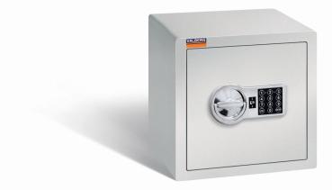 Ein lichtgrauer Möbeltresor mit einem elektronischen Schloss. Die Tür ist geschlossen. Der Tresor steht vor einem weißen Hintergrund.