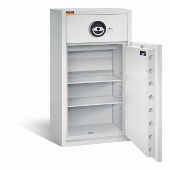 Ein lichtgrauer Deposittresor dessen Tür geöffnet ist. Im Türinnenraum befinden sich eine sichtbare Türverriegelung und ein Zertifikat. Der Innenraum ist leer und verfügt über zwei Fachböden. Der Tresor steht vor einem weißen Hintergrund.