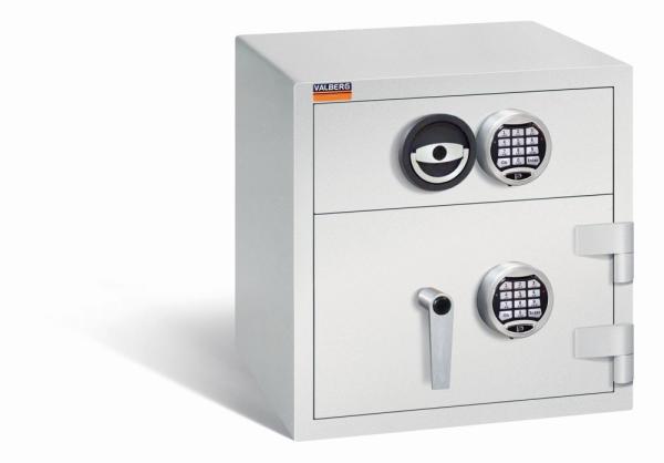 Ein lichtgrauer Deposittresor mit zwei elektronischen Schlössern, an der Tür und der Schublade. Die Tür und auch die Schublade sind verschlossen. Der Tresor steht vor einem weißen Hintergrund.