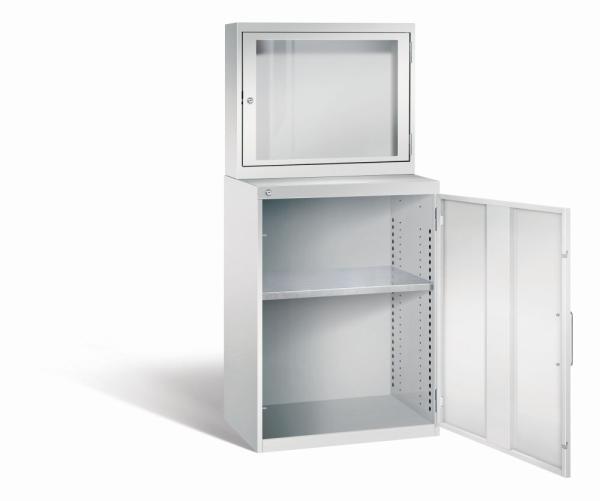 Lichtgrauer Computerschrank mit abschließbarem Sichtfenster im oberen Bereich und geöffneter Stahltür im unteren Bereich. Im unteren Fach befindet sich ein höhenverstellbarer Fachboden. Der Schrank steht vor weißem Hintergrund.