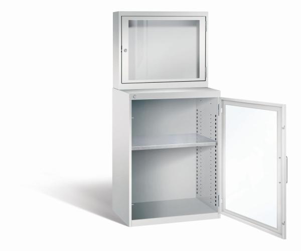 Lichtgrauer Computerschrank mit abschließbarem Sichtfenster im oberen Bereich und geöffneter Stahltür mit Sichtfenster im unteren Bereich. Im unteren Fach befindet sich ein höhenverstellbarer Fachboden. Der Schrank steht vor weißem Hintergrund.