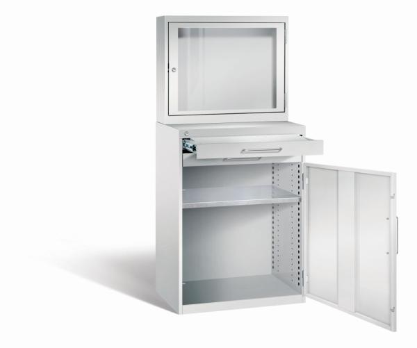 Lichtgrauer Computerschrank mit abschließbarem Sichtfenster im oberen Bereich und geöffneter Stahltür mit zwei Schubladen im unteren Bereich und einem höhenverstellbarer Fachboden. Der Schrank steht vor weißem Hintergrund.