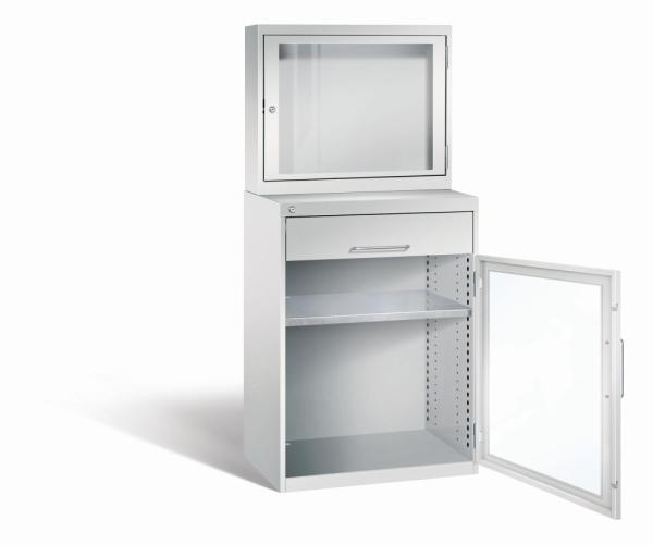 Lichtgrauer Computerschrank mit abschließbarem Sichtfenster im oberen Bereich und geöffneter Acrylglas-Stahltür im unteren Bereich mit Schublade und einem höhenverstellbarer Fachboden. Der Schrank steht vor weißem Hintergrund.