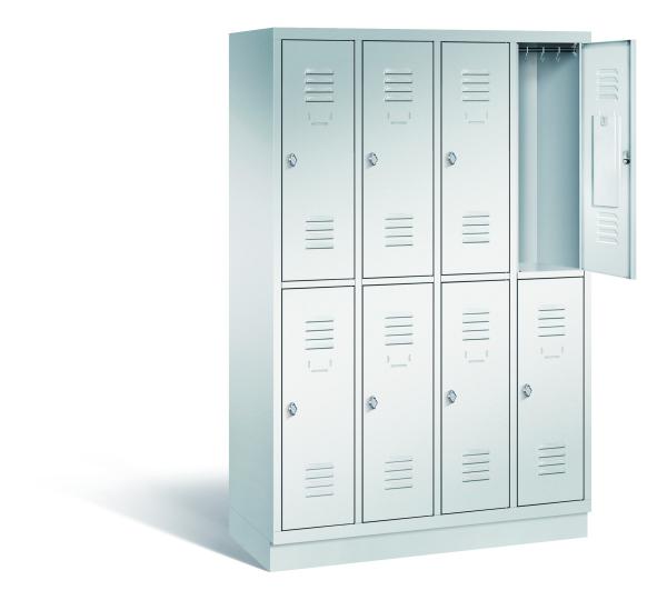 Ein lichtgrauer Garderobenschrank mit vier Abteilen, acht Fächern sowie integrierten Kleiderstangen mit Kleiderhaken, dessen obere rechte Tür geöffnet ist. Er steht auf einem Stahlblechsockel vor weißem Hintergrund.