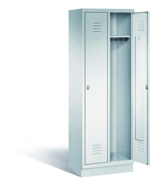 Ein lichtgrauer Garderobenschrank mit zwei Abteilen, zwei Fächern sowie integrierten Kleiderstangen mit Kleiderhaken, dessen rechte Tür geöffnet ist. Er steht auf einem Stahlblechsockel vor weißem Hintergrund.