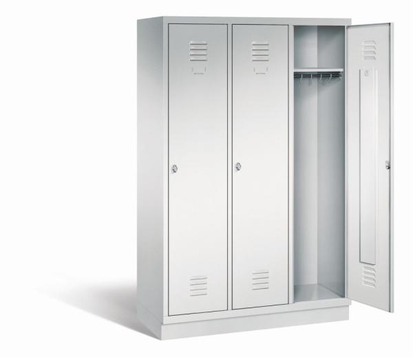 Ein lichtgrauer Garderobenschrank mit drei Abteilen, drei Fächern sowie integrierten Kleiderstangen mit Kleiderhaken, dessen rechte Tür geöffnet ist. Er steht auf einem Stahlblechsockel vor weißem Hintergrund.