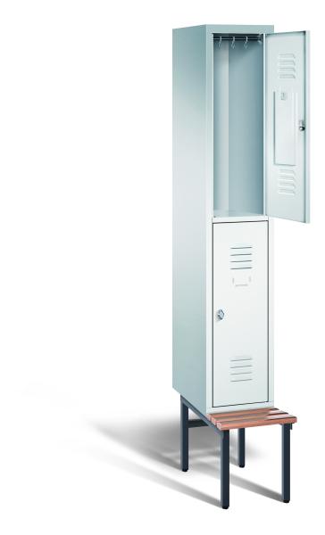 Ein lichtgrauer Garderobenschrank mit einem Abteil, zwei Fächern sowie integrierten Kleiderstangen mit Kleiderhaken, dessen obere Tür geöffnet ist. Er steht auf einer unter- und vorgebauten Sitzbank vor weißem Hintergrund.