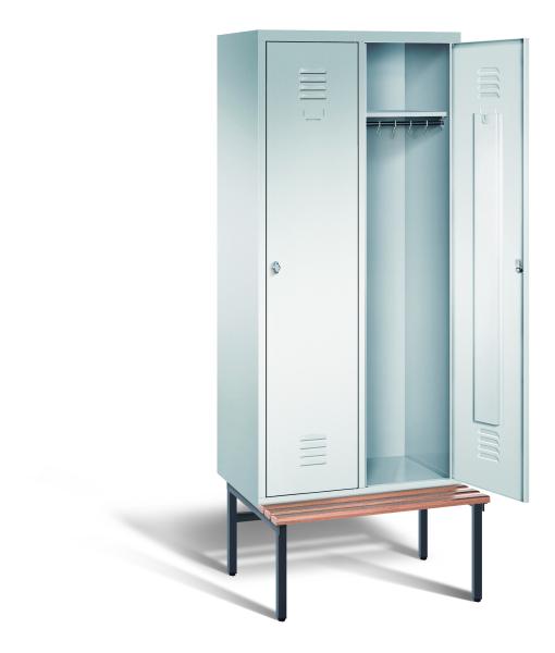 Ein lichtgrauer Garderobenschrank mit zwei Abteilen, zwei Fächern sowie integrierten Kleiderstangen mit Kleiderhaken, dessen rechte Tür geöffnet ist. Er steht auf einer unter- und vorgebauten Sitzbank vor weißem Hintergrund.